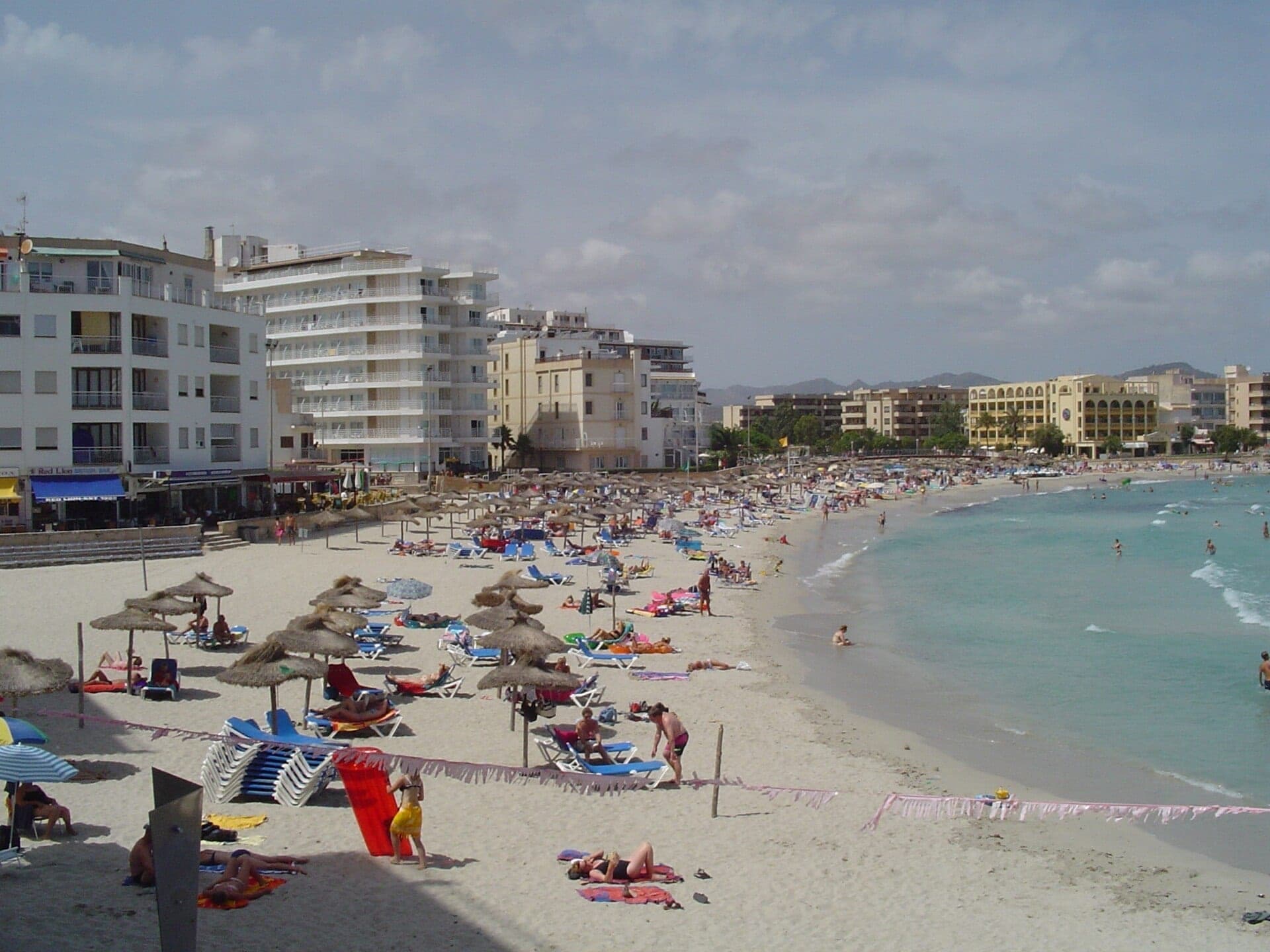 La playa urbana de arena de S'Illot con el pueblo detrás.